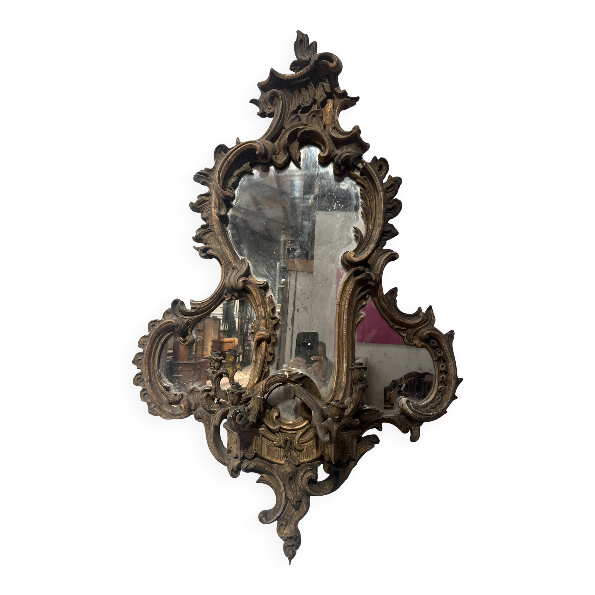 Mirror with a decorative frame featuring a four-light wall sconce, 19th century.