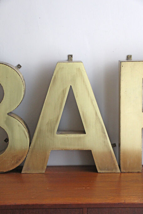 Old brass sign letters, word BAR