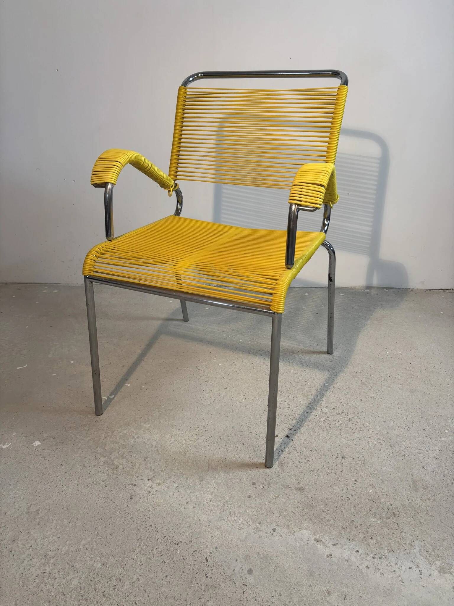 Yellow scoubidou armchair with a chrome tubular frame.