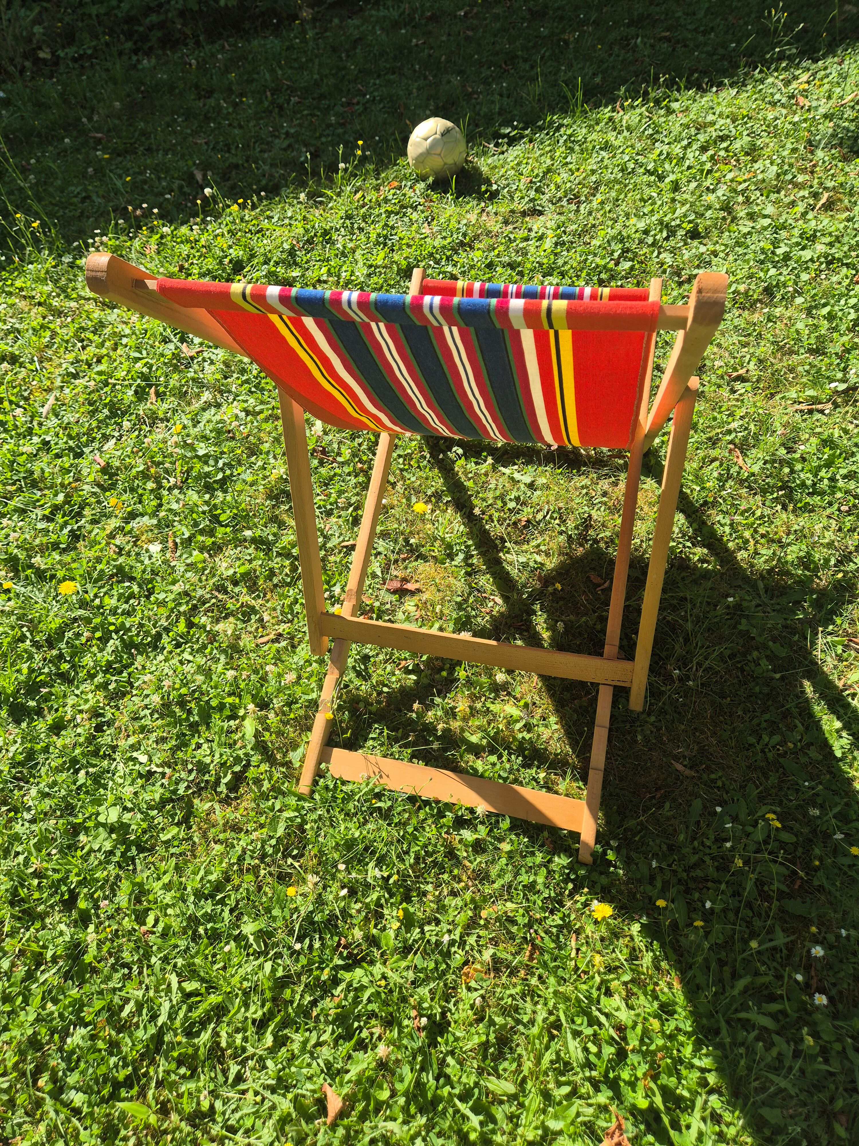 vintage wooden deck chair with red, blue, and yellow striped fabric