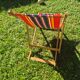 vintage wooden deck chair with red, blue, and yellow striped fabric