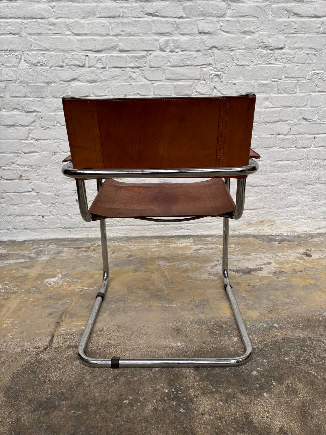 Vintage aluminum tube and tan leather armchair
