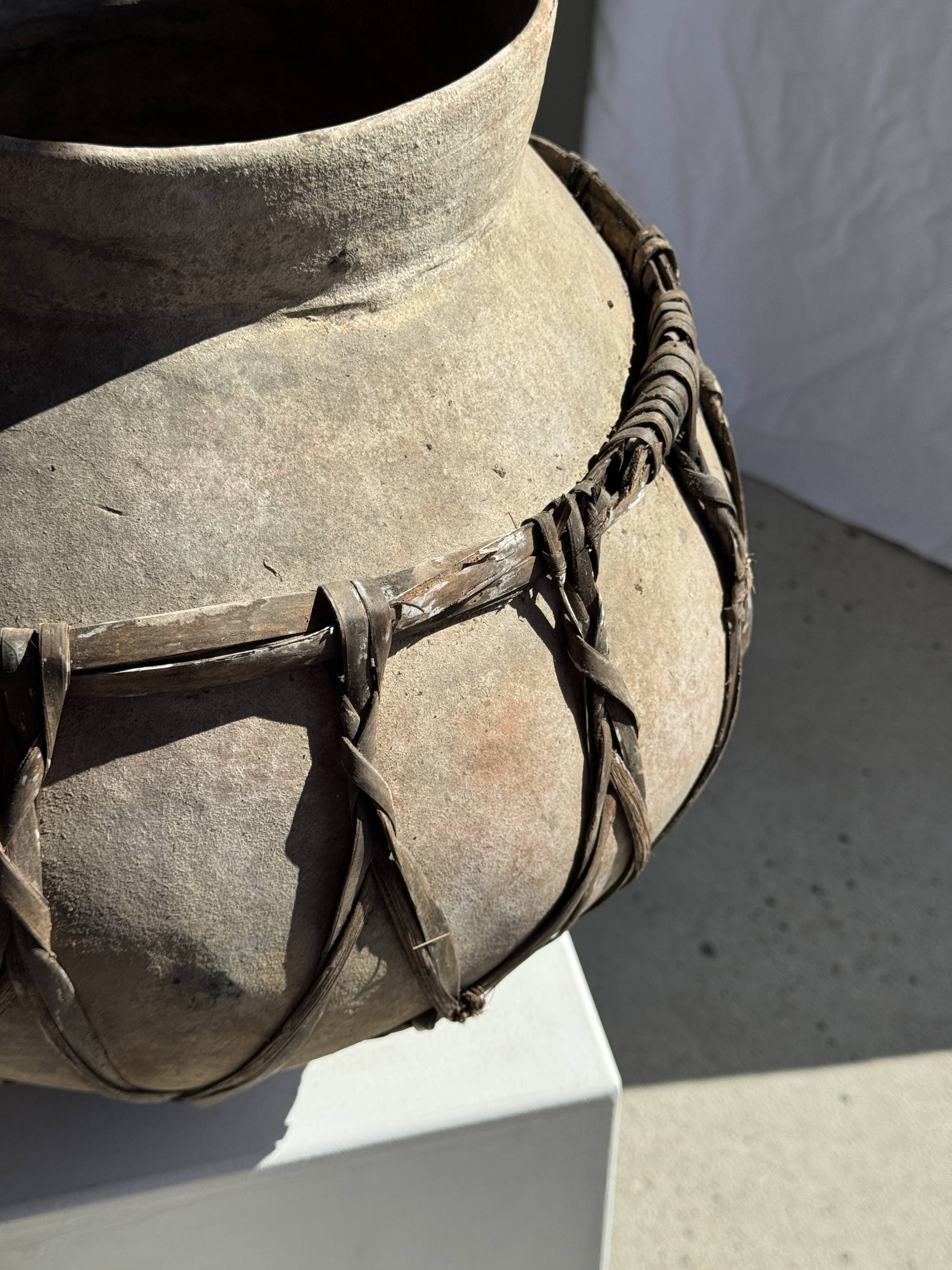 Very large light grey terracotta pot with handles and rattan crossbars.