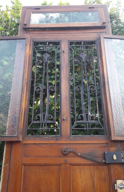 Oak entrance door and its frame and transom, wrought iron gates