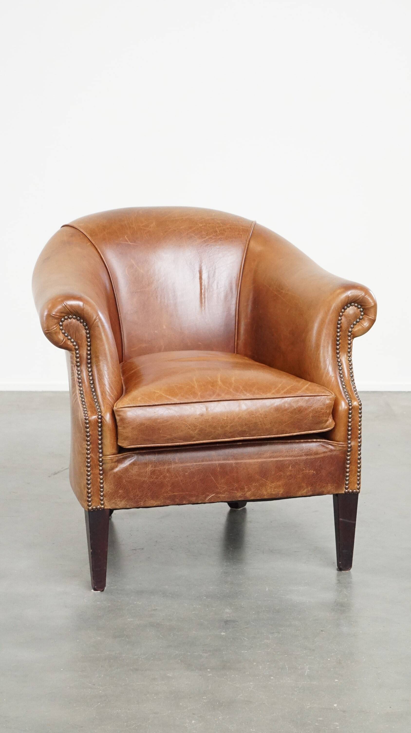 Very comfortable, elegant leather club armchair with a removable seat cushion and timeless design