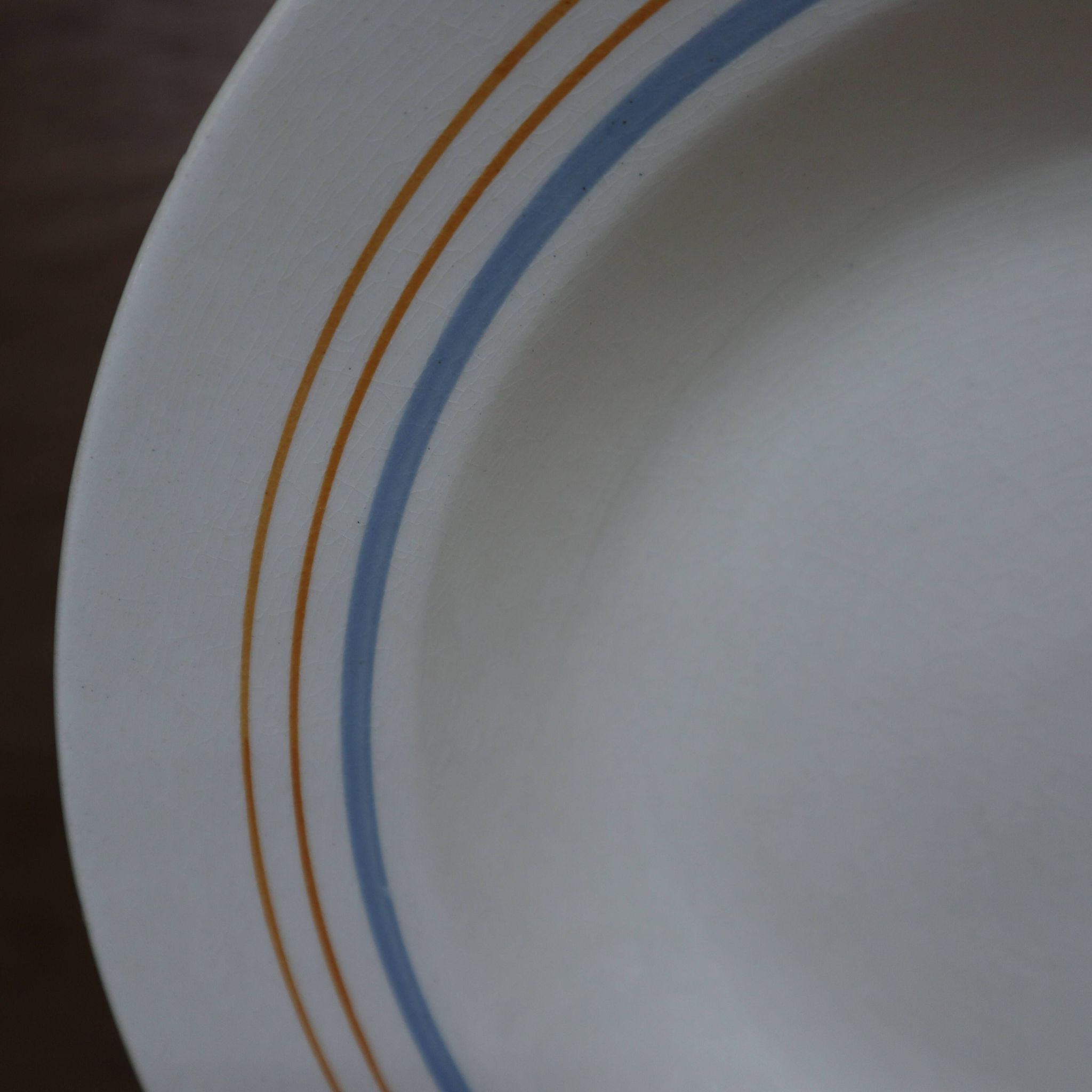6 old cream-coloured deep plates with blue/orange trim.