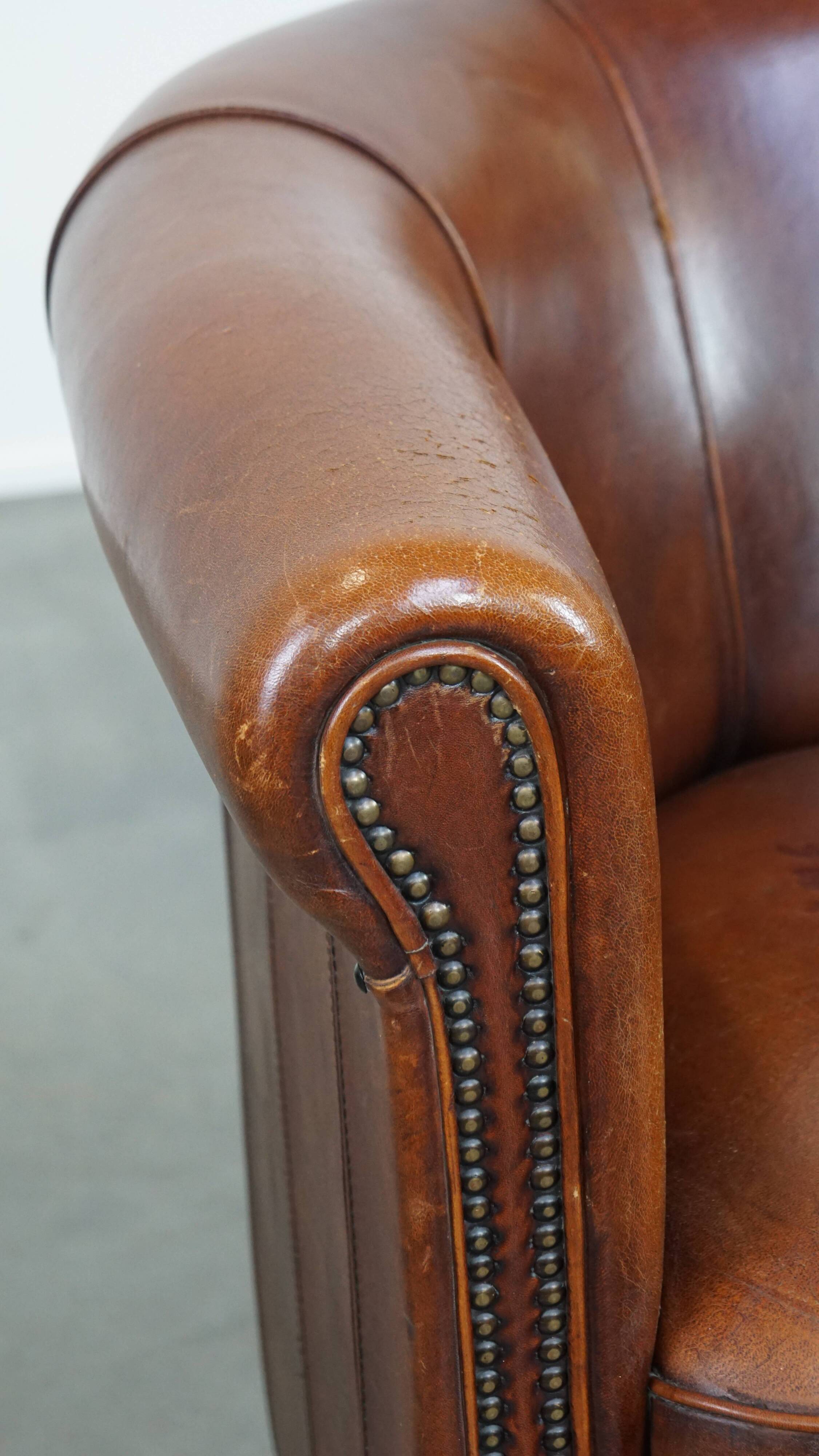 Sheep leather club chair in a cognac color and finished with piping