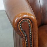 Sheep leather club chair in a cognac color and finished with piping