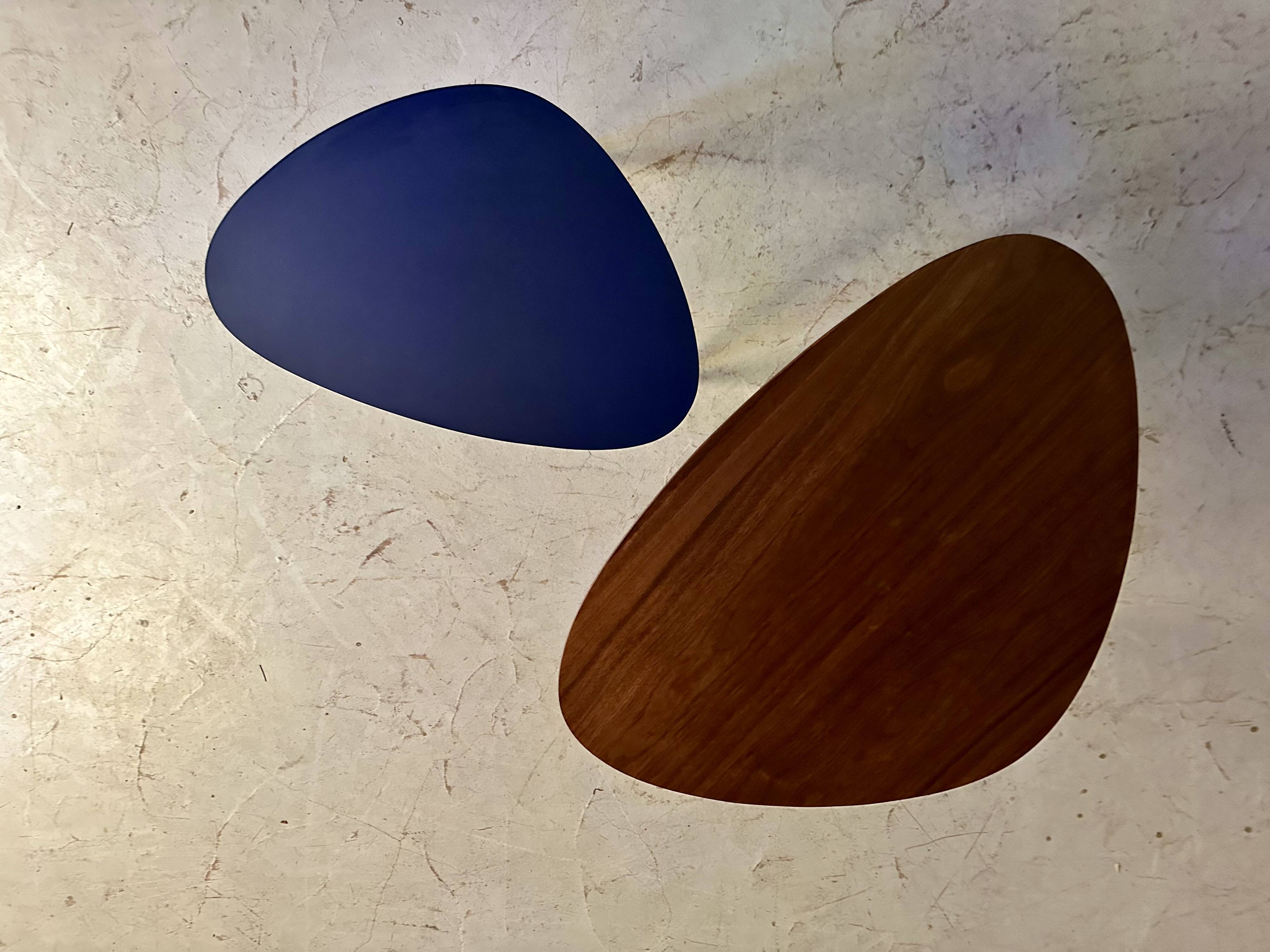 A pair of tripod and nesting coffee tables in walnut and midnight blue.