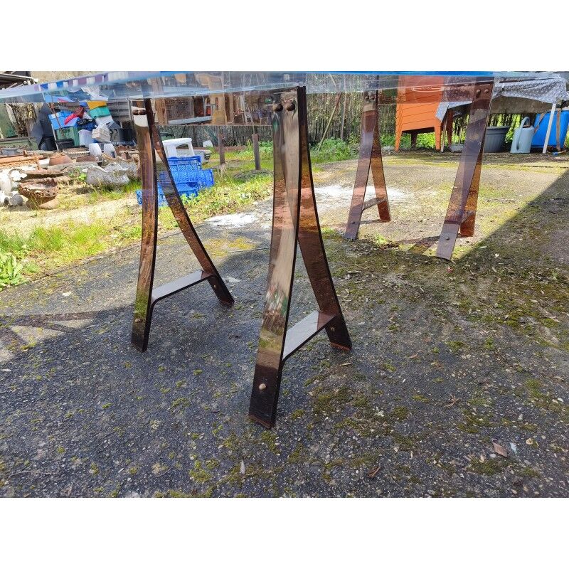 Vintage table with a glass top and smoked plastic trestle legs.