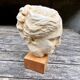 Plaster head of an ancient goddess on its wooden base