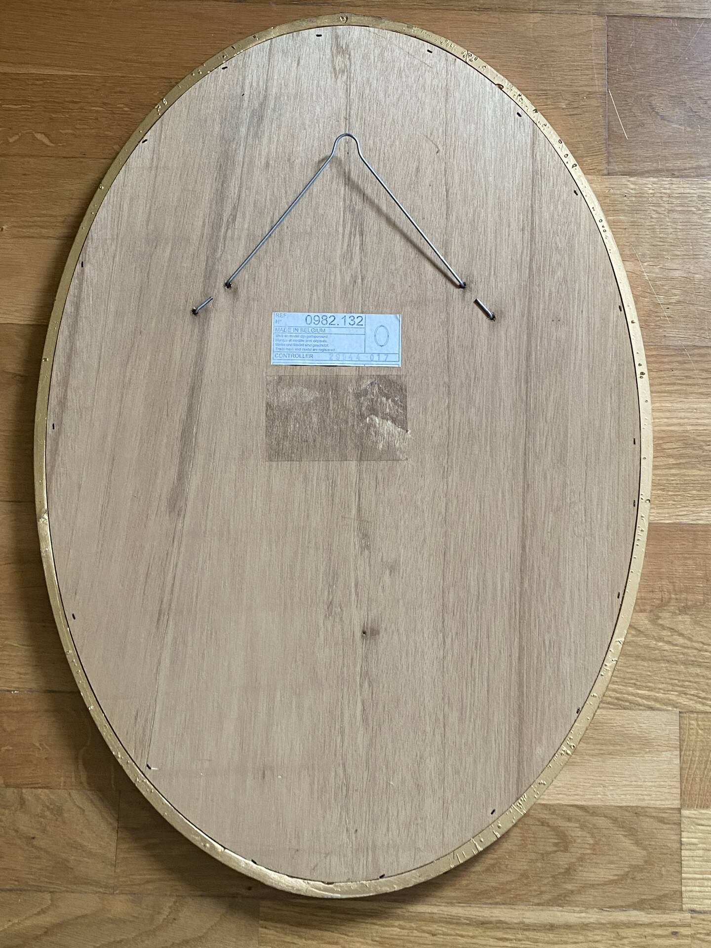 Oval wooden frame with floral decoration in gold.