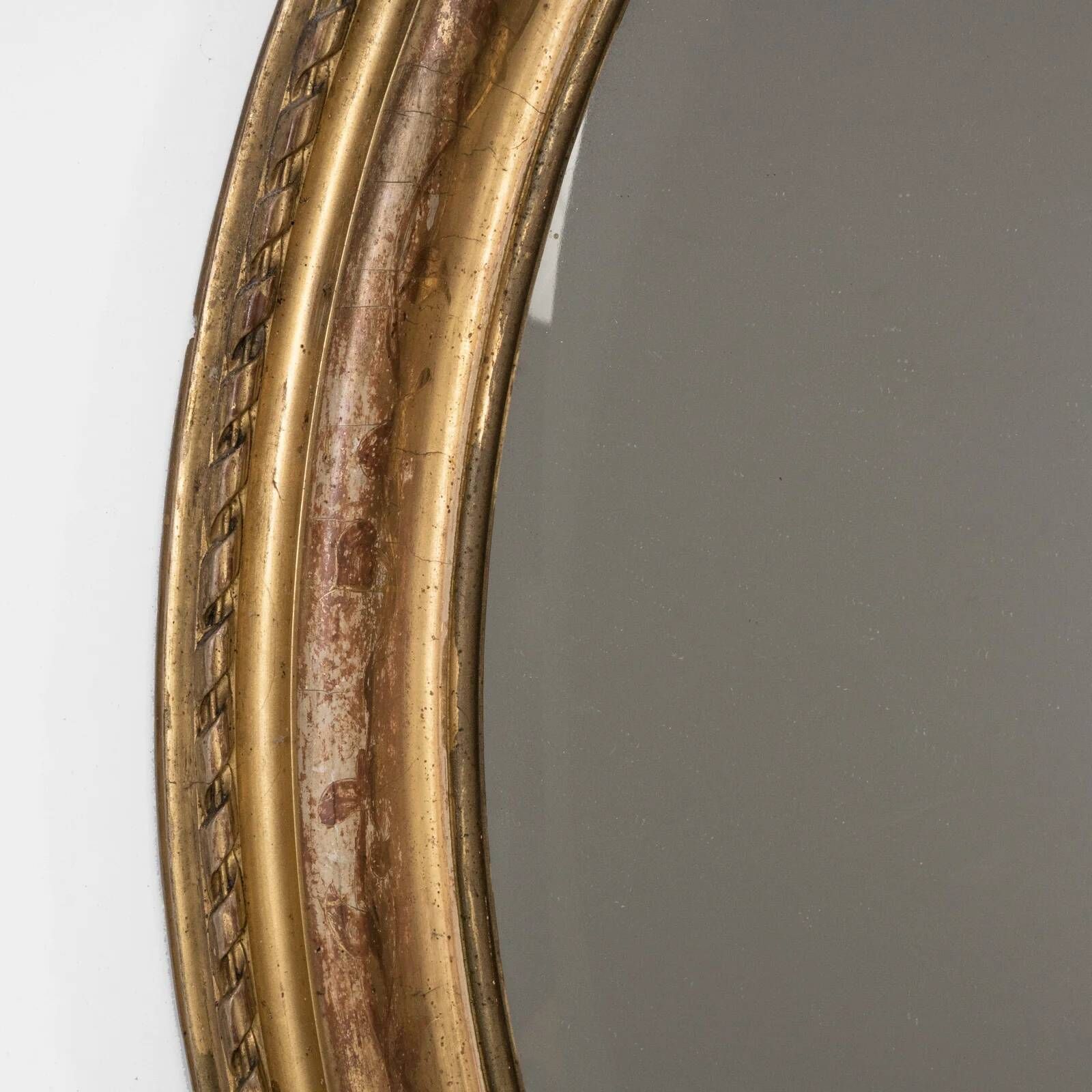 French 19th-century oval mirror in gold leaf with a pediment.