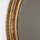 French 19th-century oval mirror in gold leaf with a pediment.