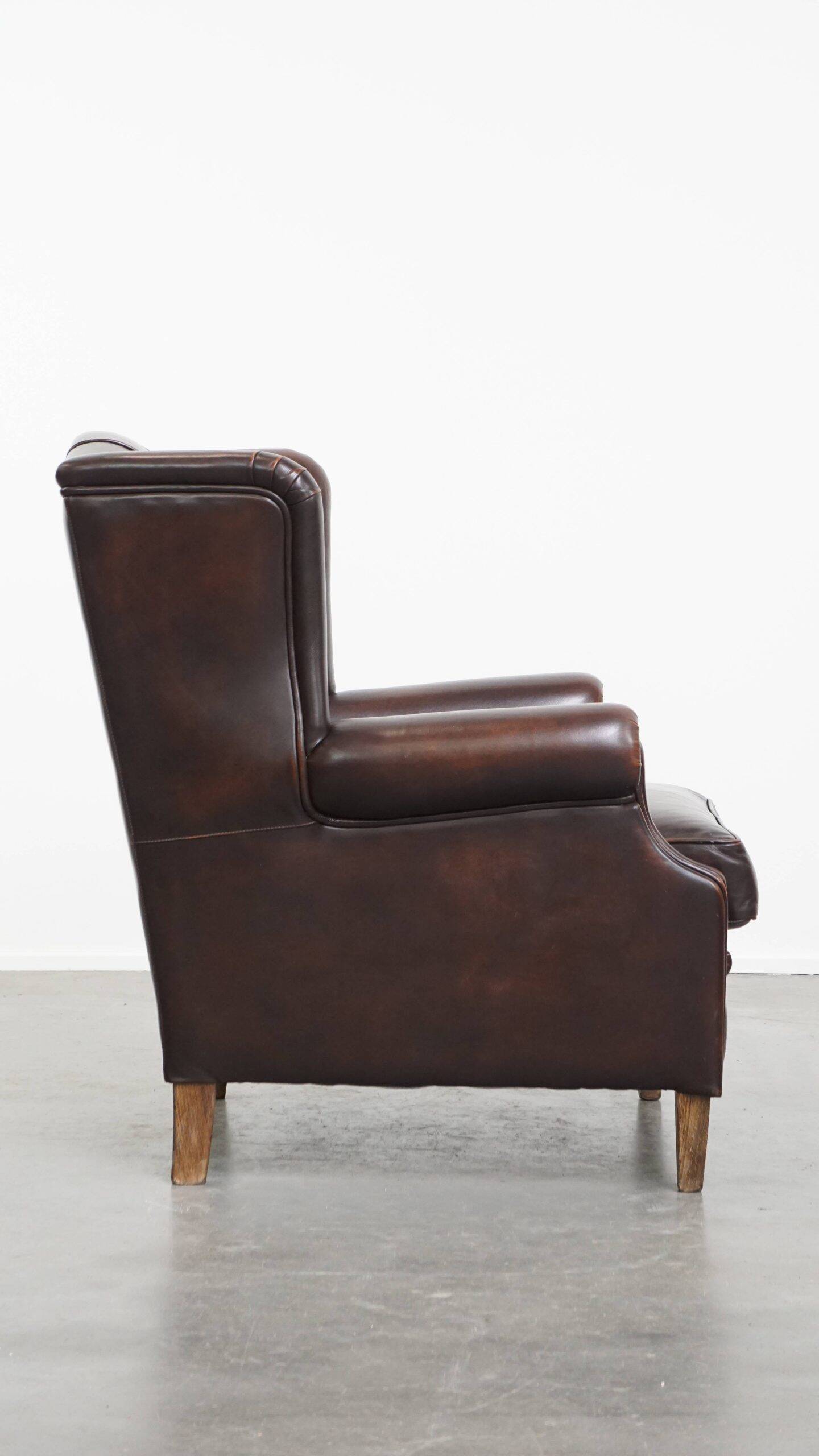 Comfortable wingback chair in English style made of cowhide leather