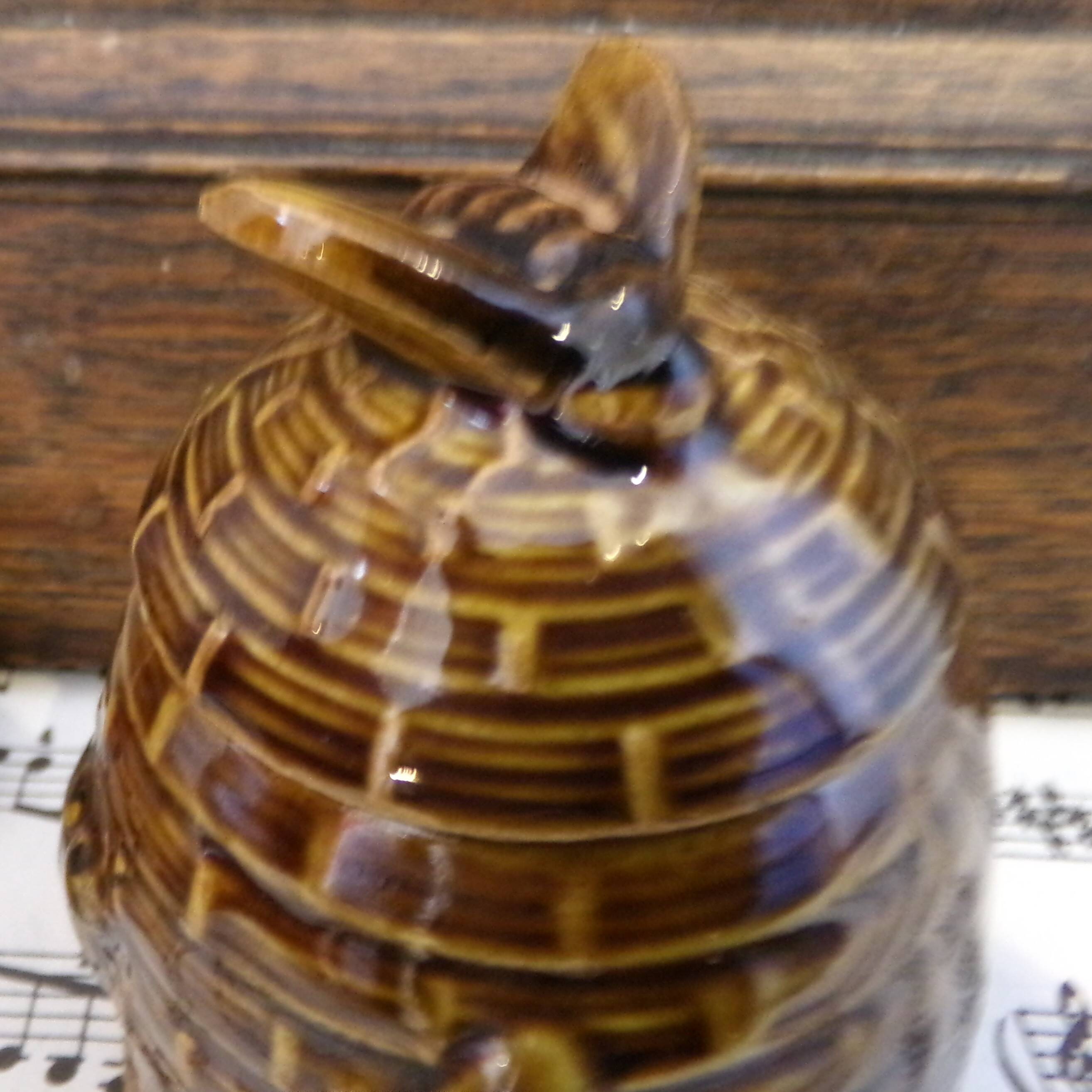 Honey pot in the shape of a hive decorated with bees.
