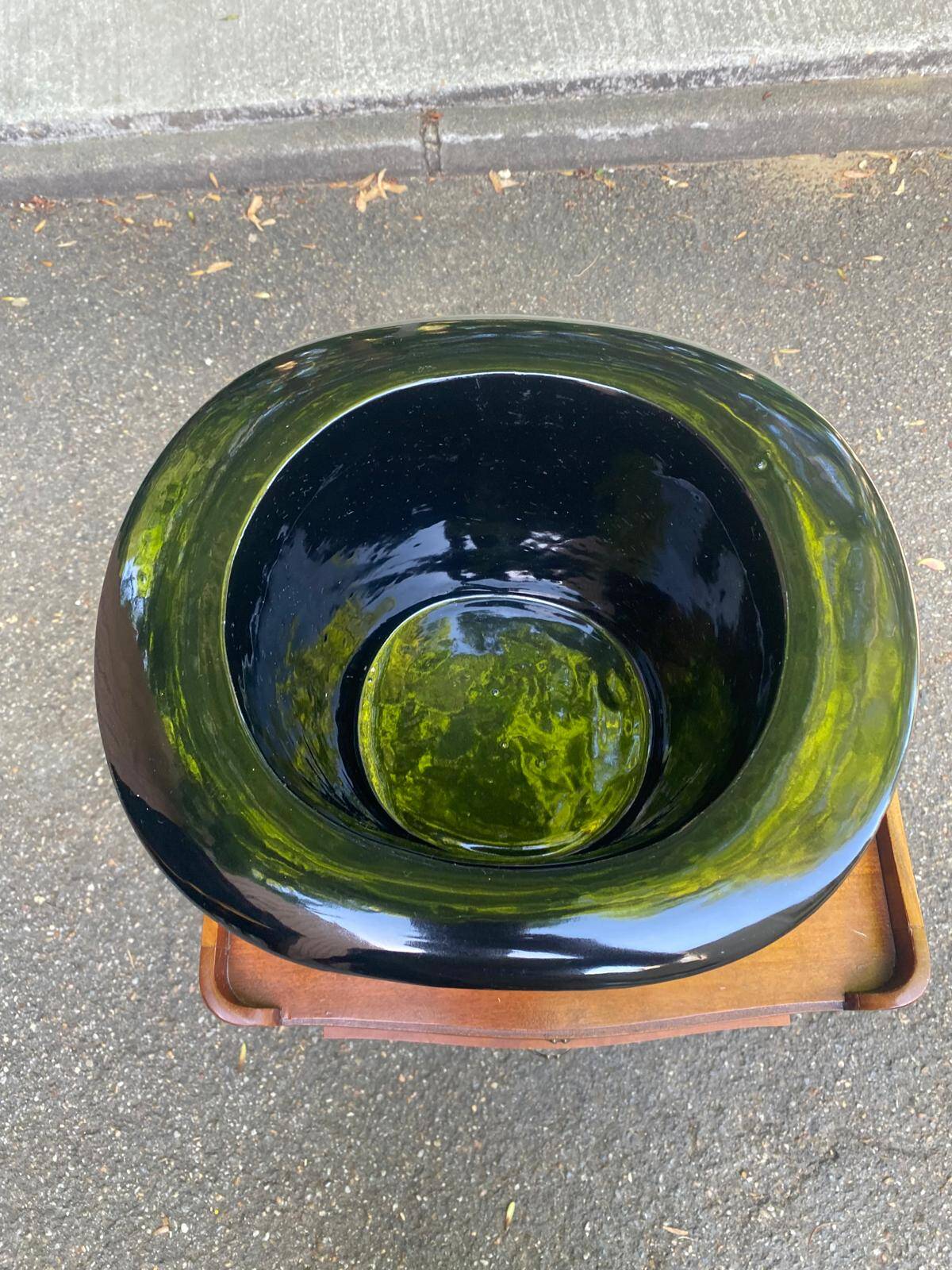 A black top hat-shaped vale turned upside down from the 1960s.