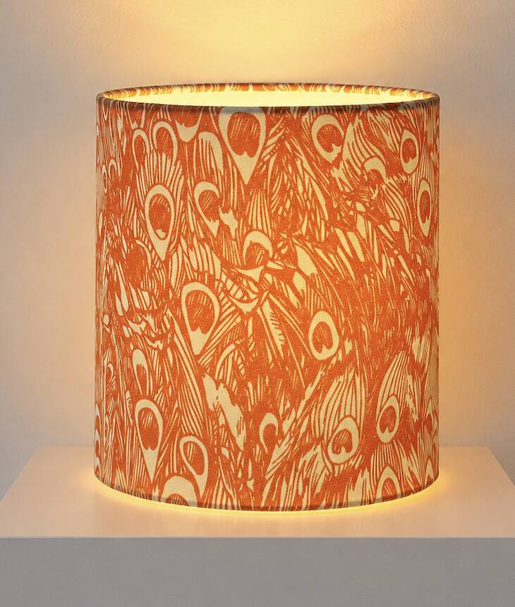 Lampshade covered with a decorative translucent fabric featuring a peacock pattern.