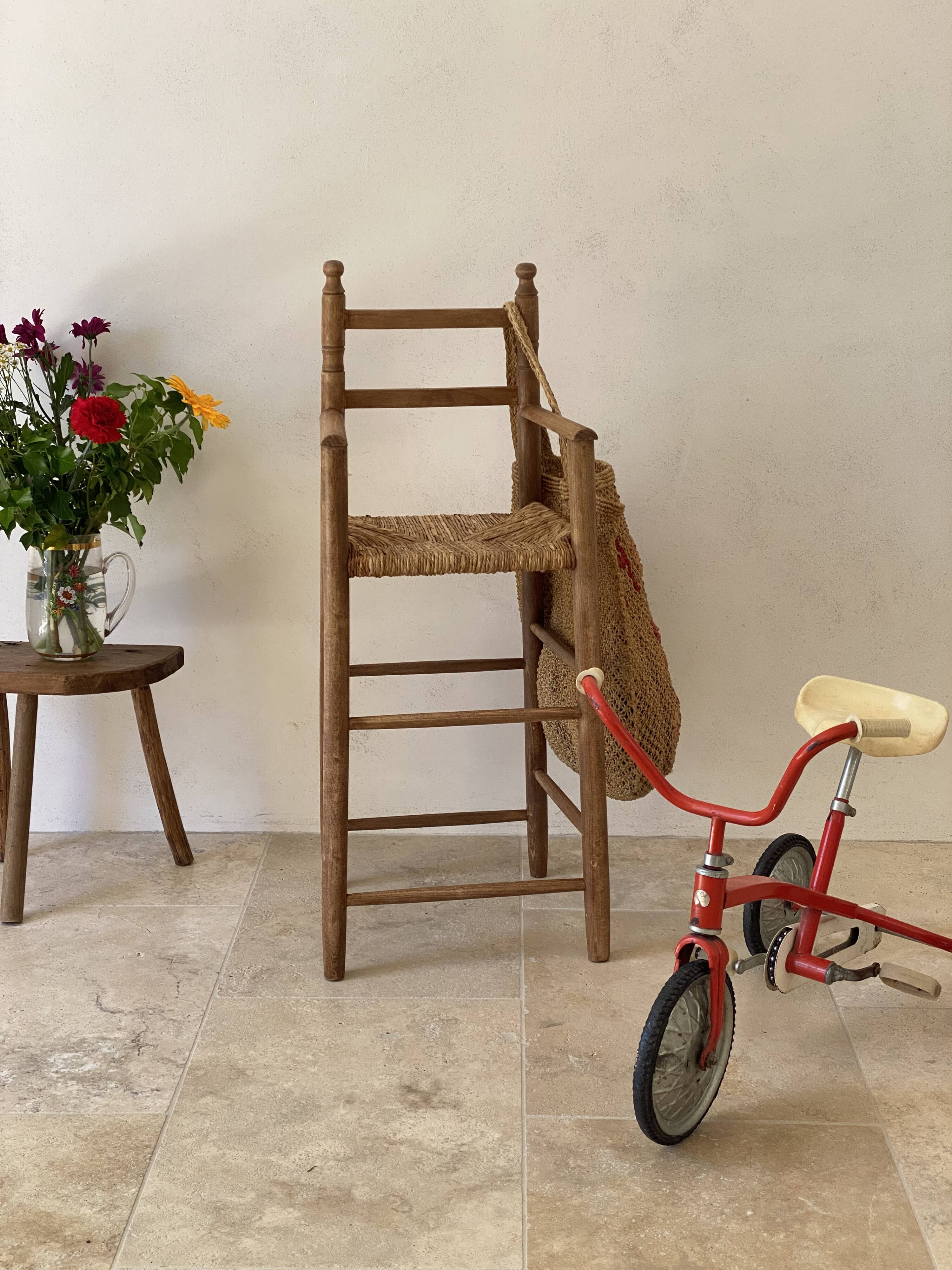 Old wooden high chair for children with a straw seat.