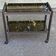 Vintage 1970s rolling bar cart made of metal and smoked glass.