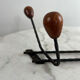 Wall-mounted coat rack in wrought iron with turned wooden knobs.
