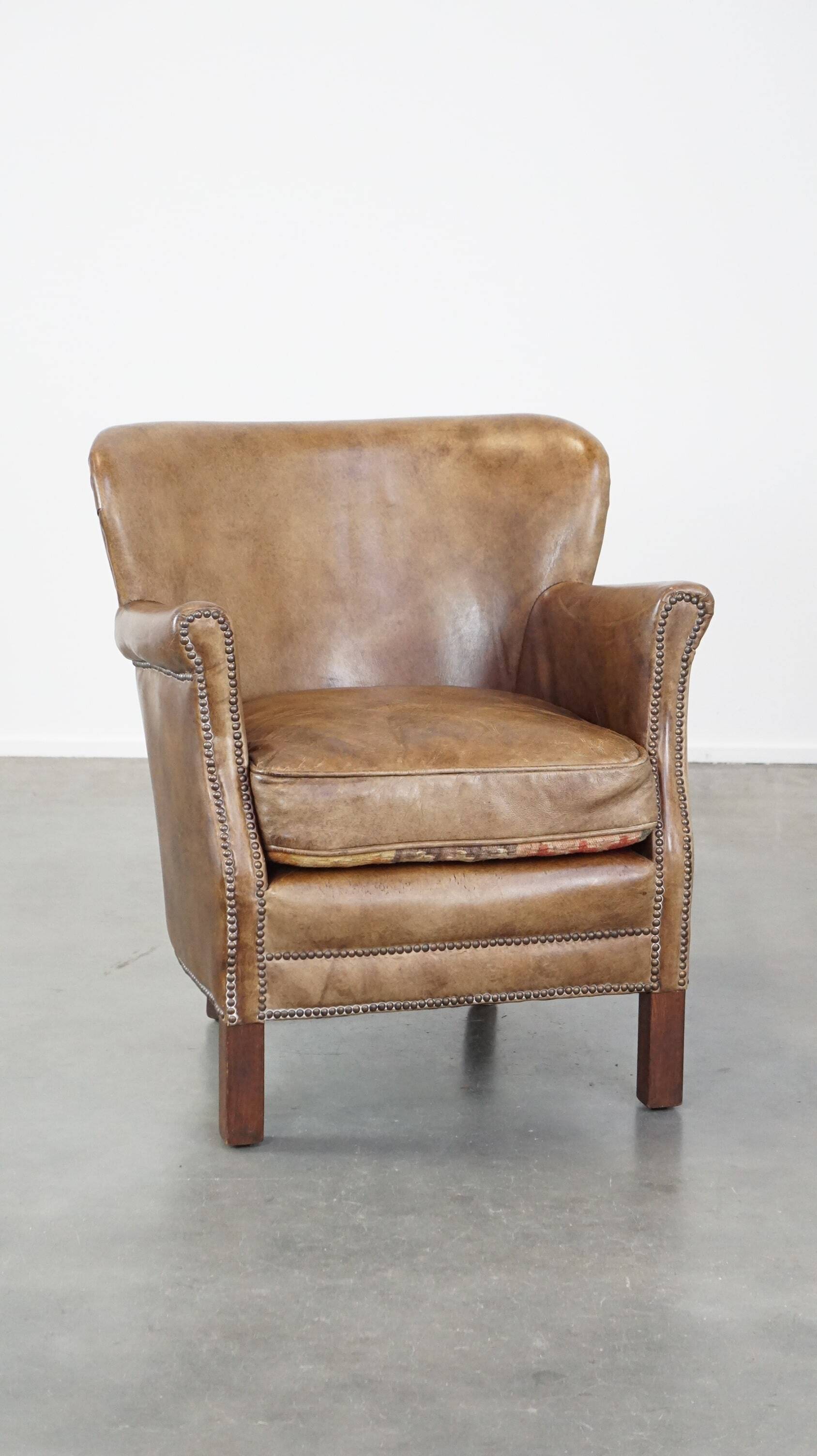 Subtle leather armchair with a reversible kilim seat cushion