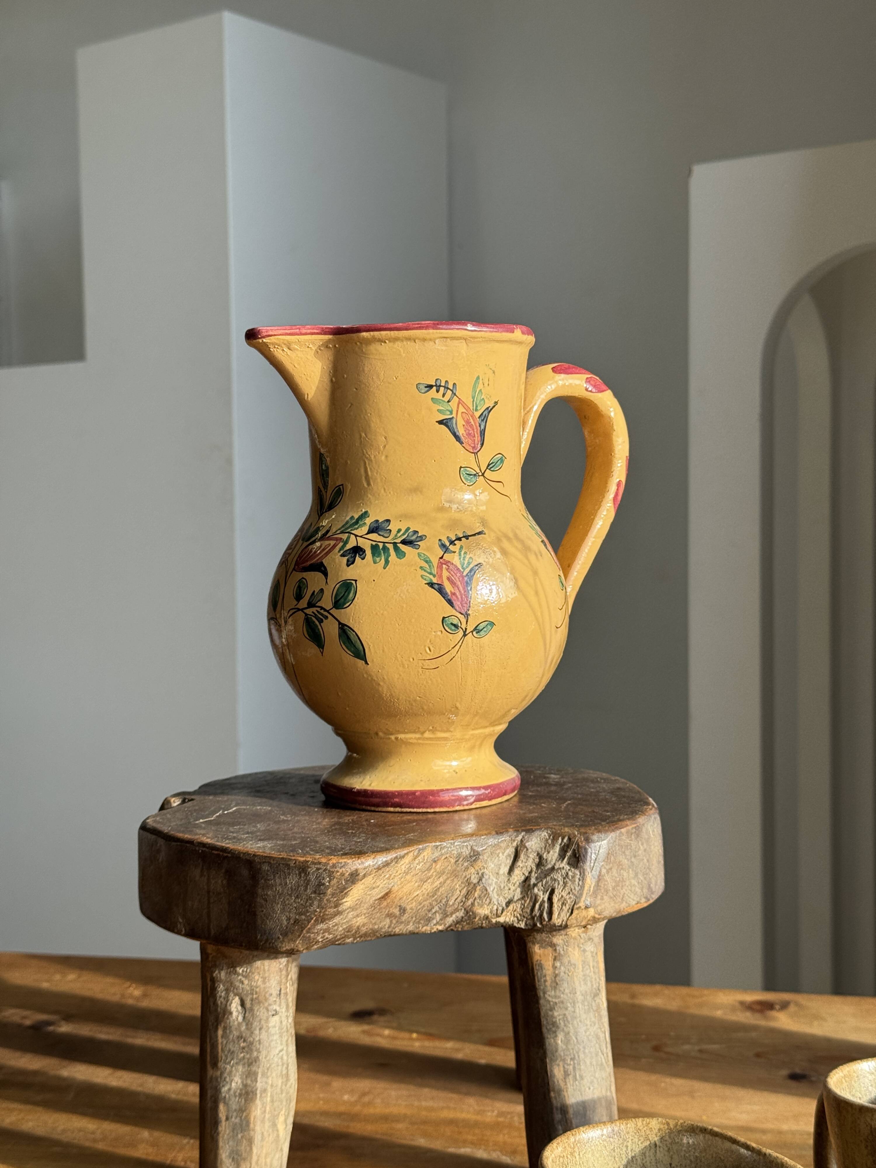 Large antique handmade ochre yellow jug with a pink flower pattern.