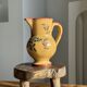 Large antique handmade ochre yellow jug with a pink flower pattern.