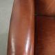 Sheepskin wingback armchair in a warm cognac colour with refined nailhead trim