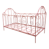 Old iron bed for children, painted pink with scrolls, romantic style.