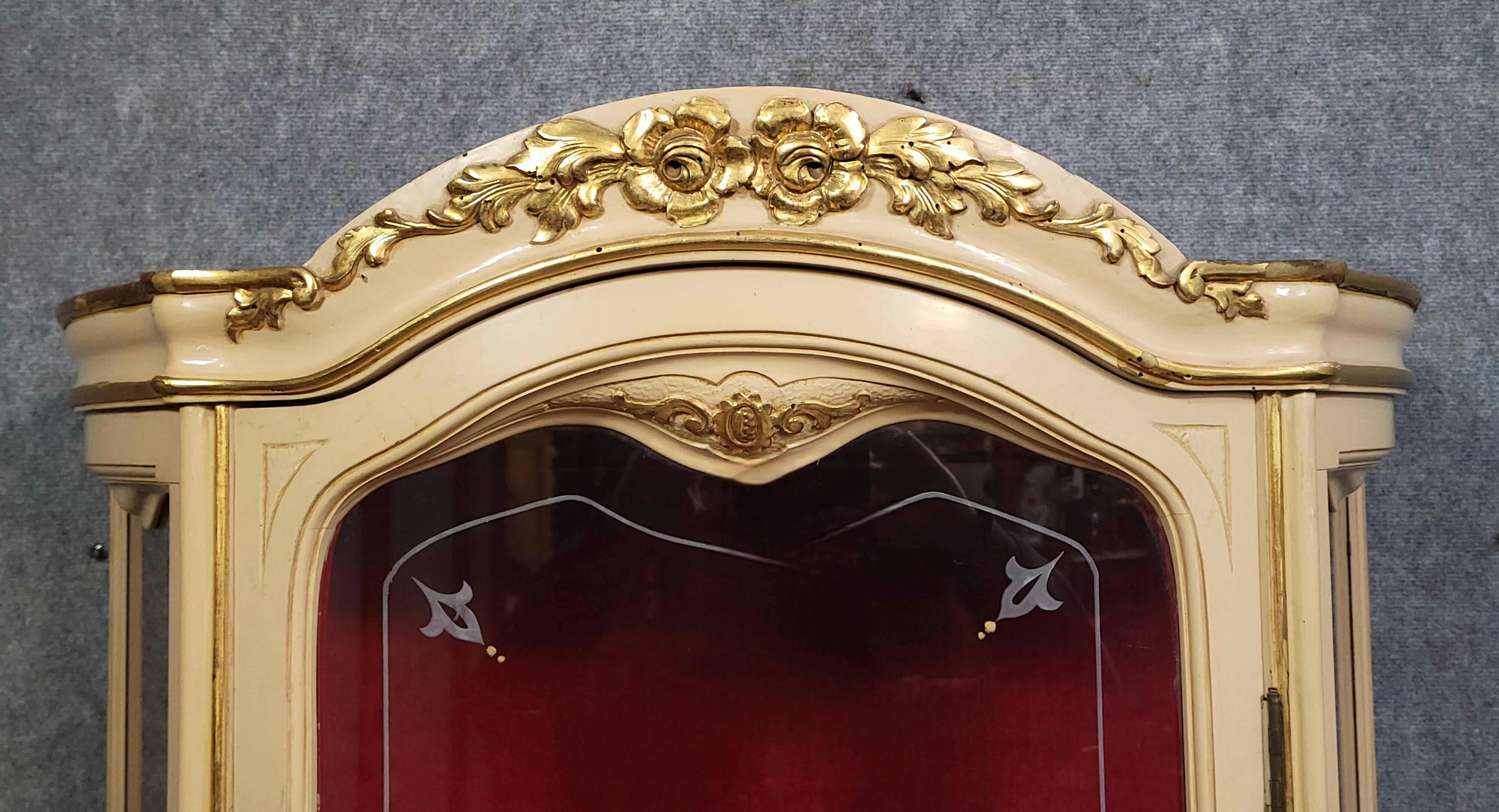 Curved display cabinet in Louis XV style, in cream lacquered wood enhanced with gilding.