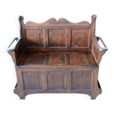 Antique brown oak bench with storage chest and panelled carved backrest.