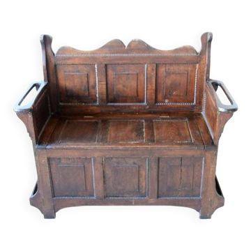 Antique brown oak bench with storage chest and panelled carved backrest.