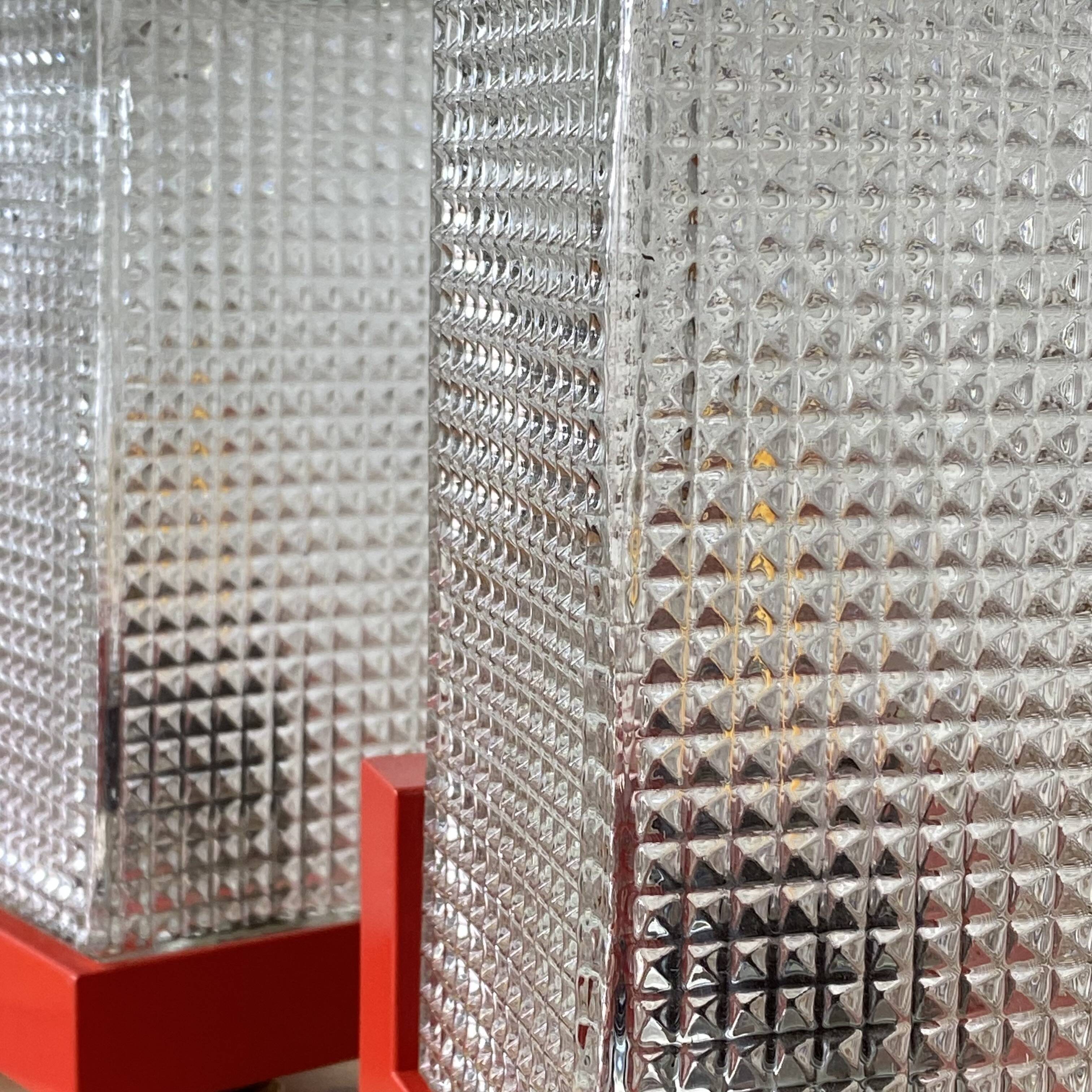 Pair of vintage wall lights in red plastic and clear glass.