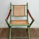 Paire de chaises safari pliantes façon faux-bambou patiné, dossiers et assises cannées et repose-bras en cuir