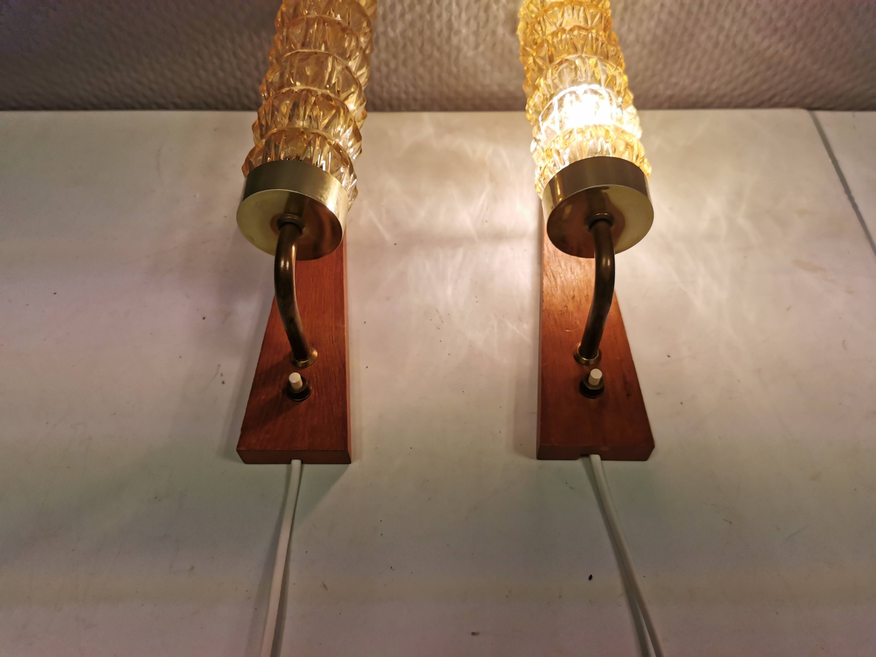 A set of Danish wall lights in champagne coloured glass with brass and teak.