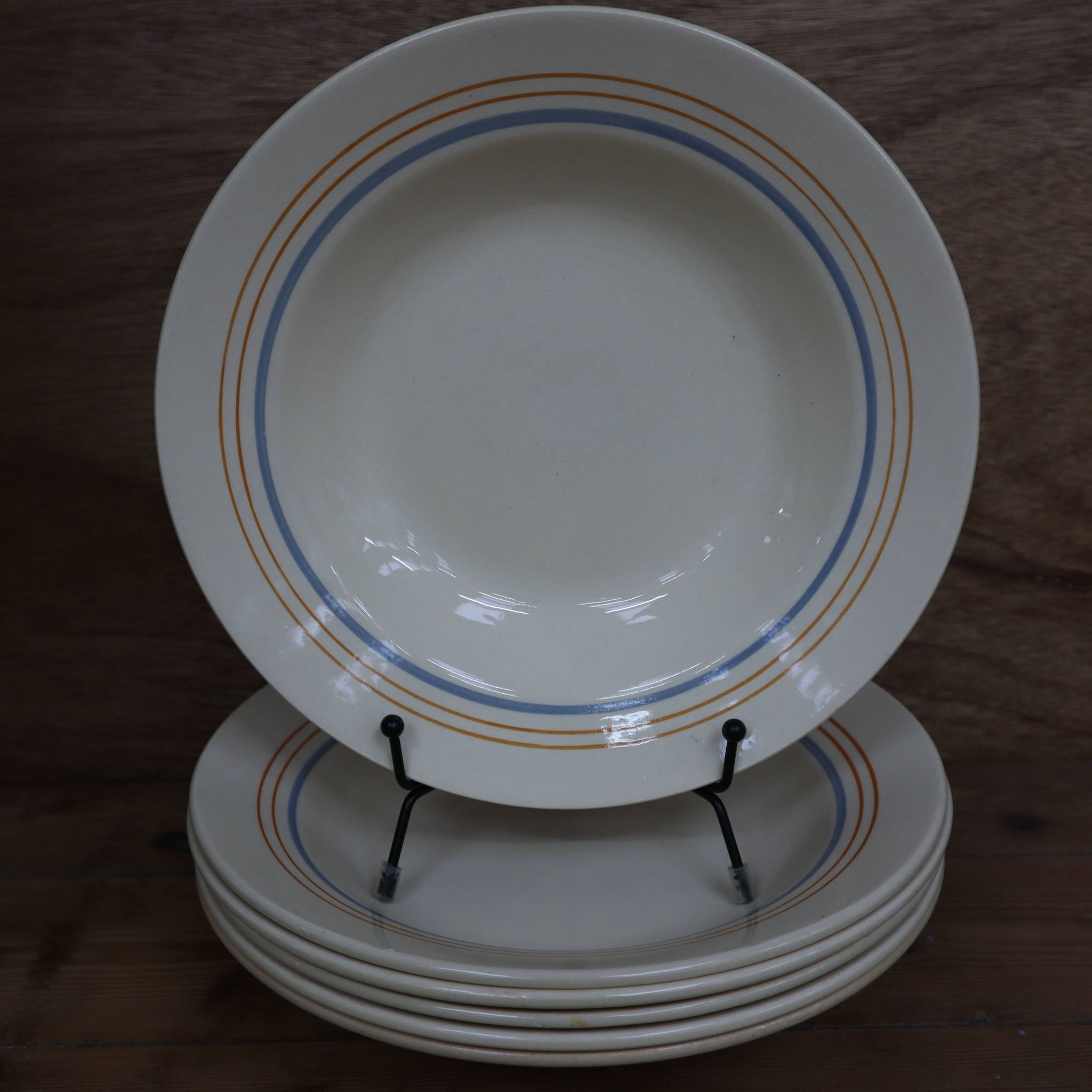 6 old cream-coloured deep plates with blue/orange trim.
