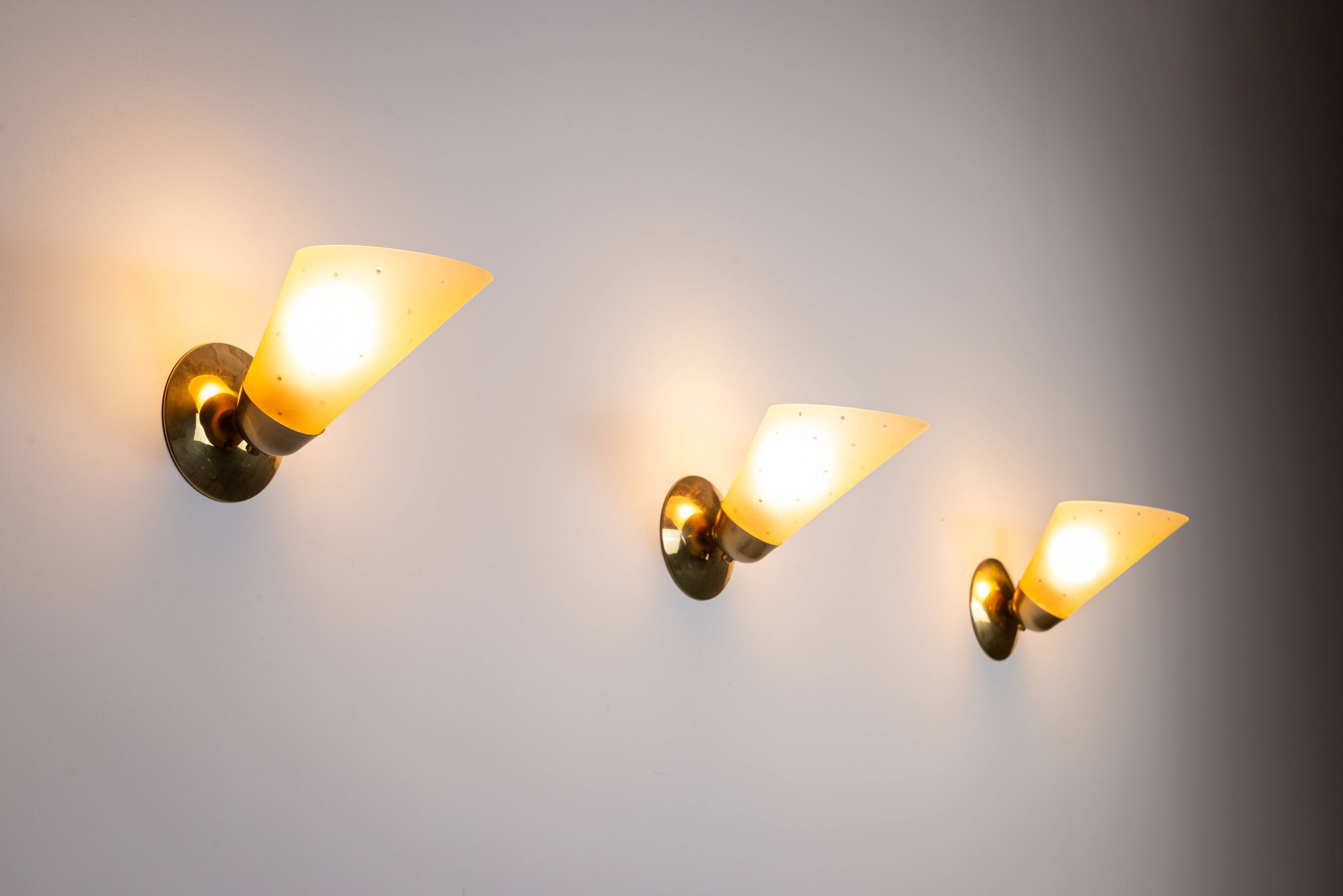 Set of three brass sconces with decorated yellow glass shades