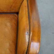 Unique, luxurious sheepskin armchair combined with wood and finished with decorative nails