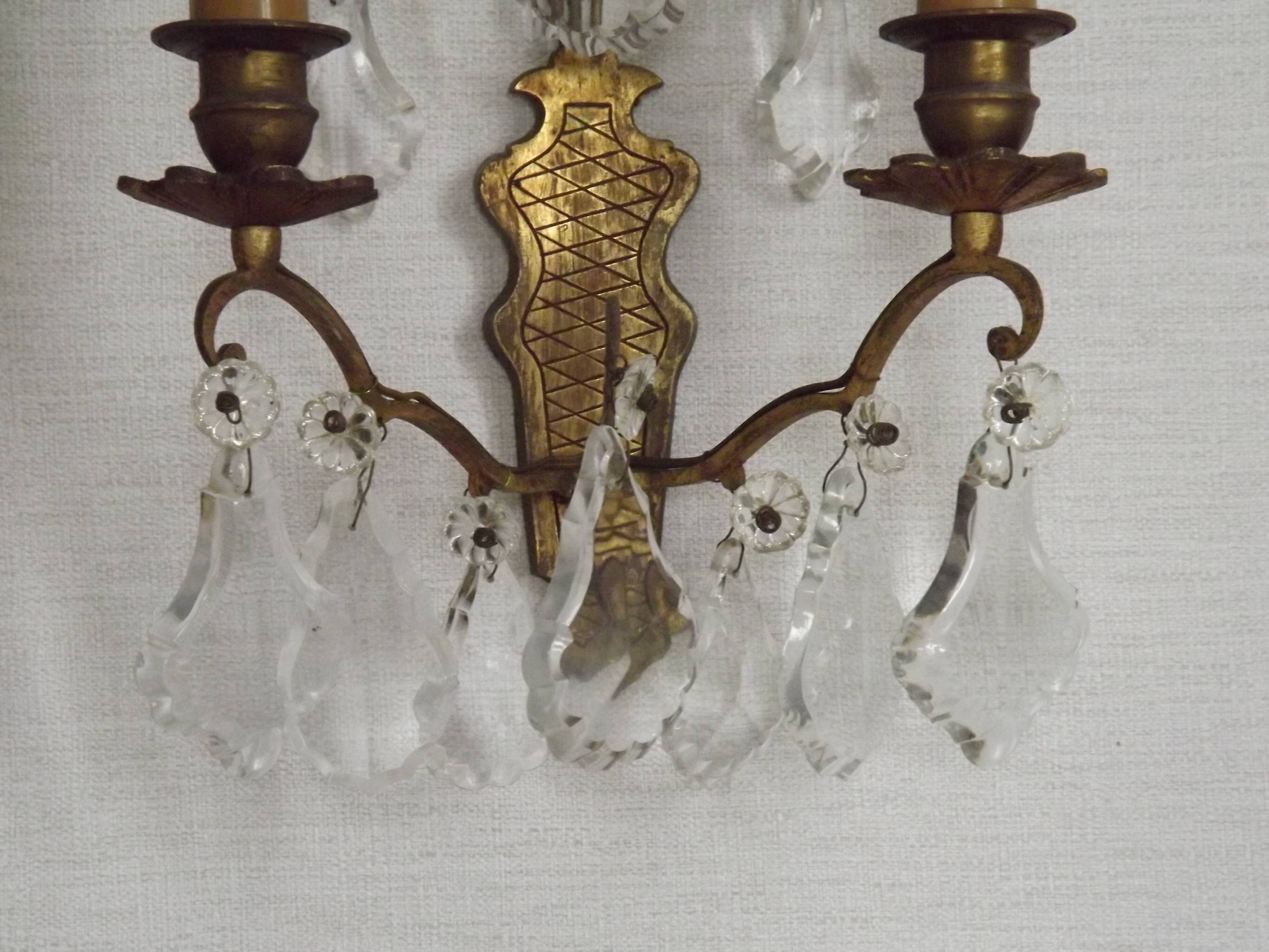 Pair of French antique brass double wall lights with assorted crystals.