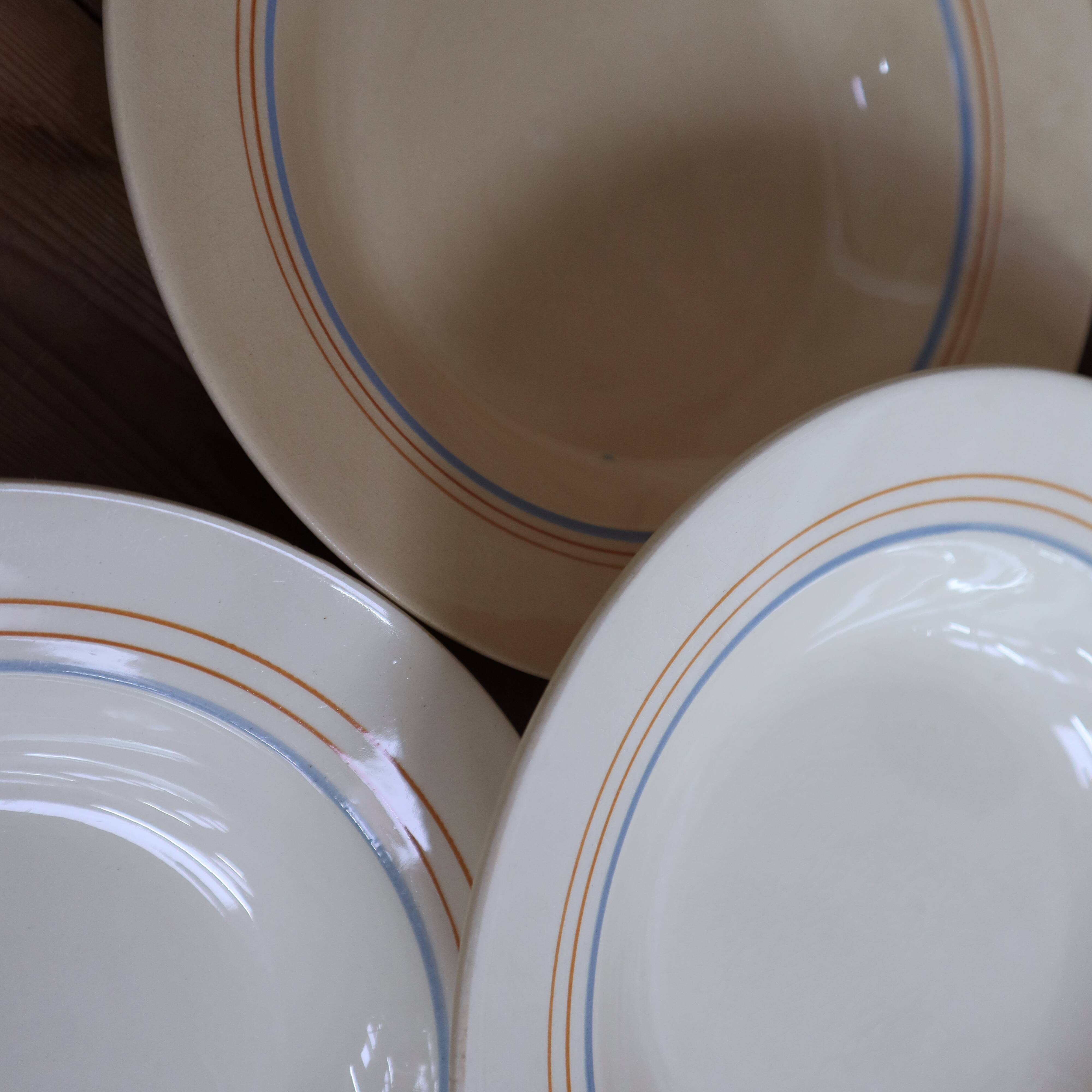 6 old cream-coloured deep plates with blue/orange trim.