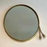 Oval brass mirror surrounded by a cord and adorned