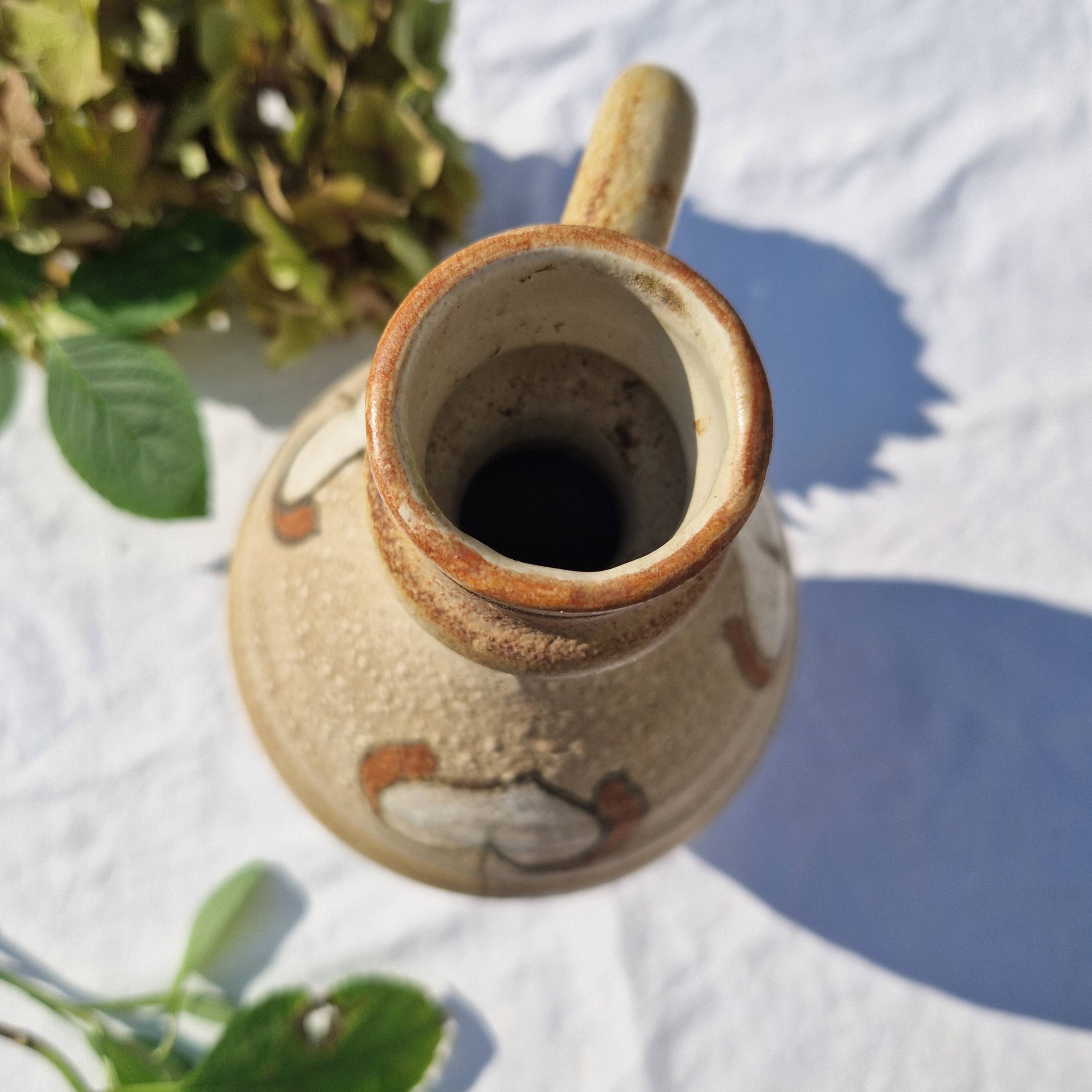 Handcrafted jug or jar with a handle, terracotta pottery vase, fat lava effect, stylized flowers