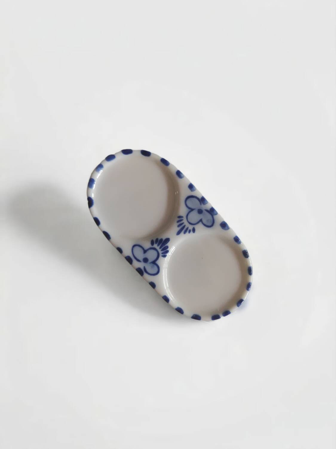 Mini salt and pepper shakers in ceramic with illustrations of Dutch windmills and blue flowers.