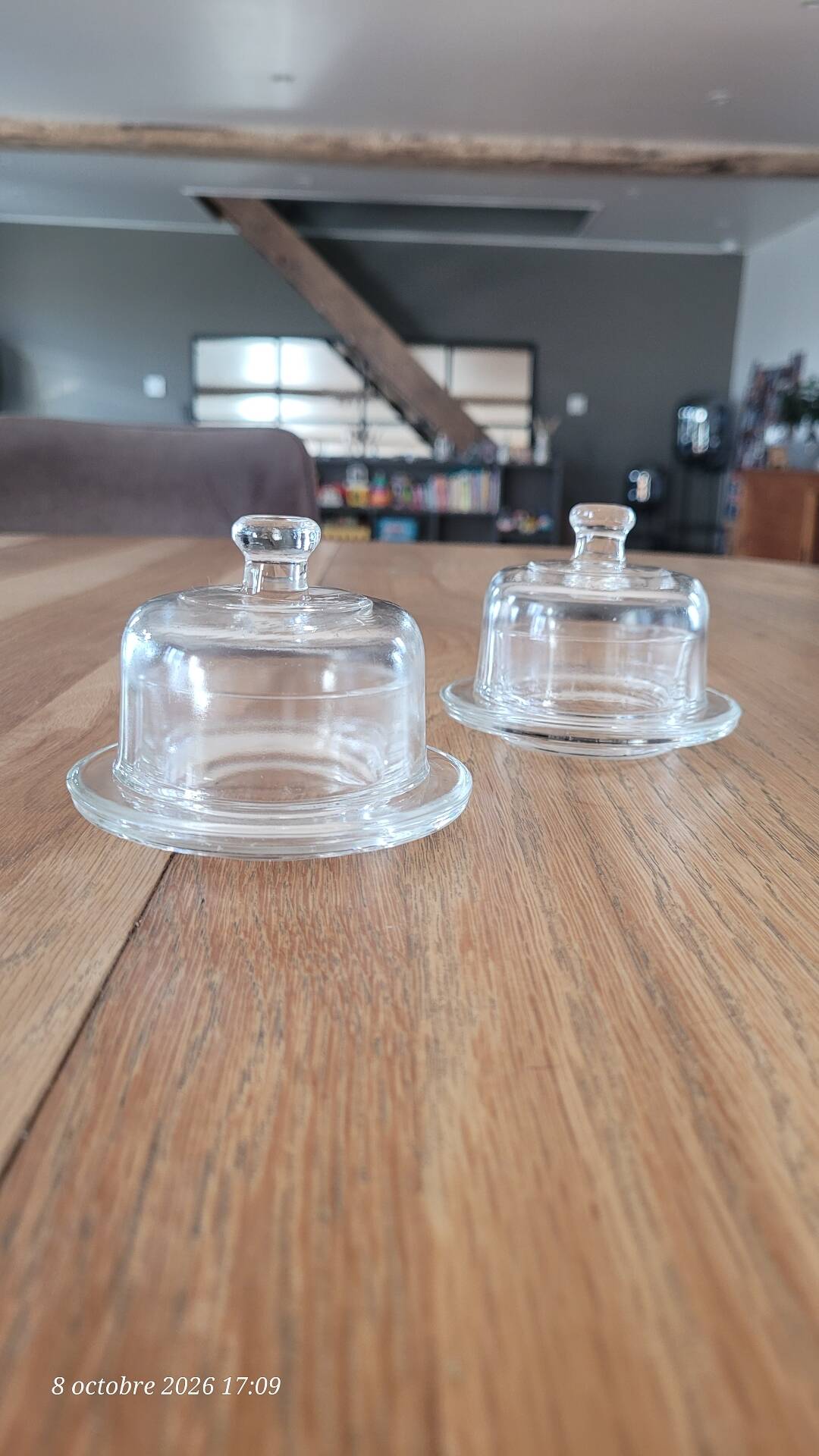 2 transparent glass butter dishes accompanied by their matching cloches.