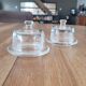2 transparent glass butter dishes accompanied by their matching cloches.