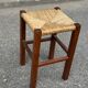 Low stool in brutalist style made of solid wood with straw, 1980.