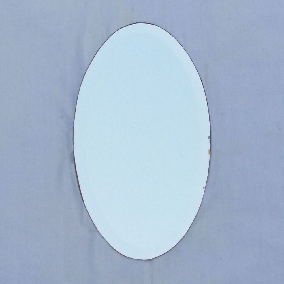 Beveled oval mirror stitched at the edges around the 1930