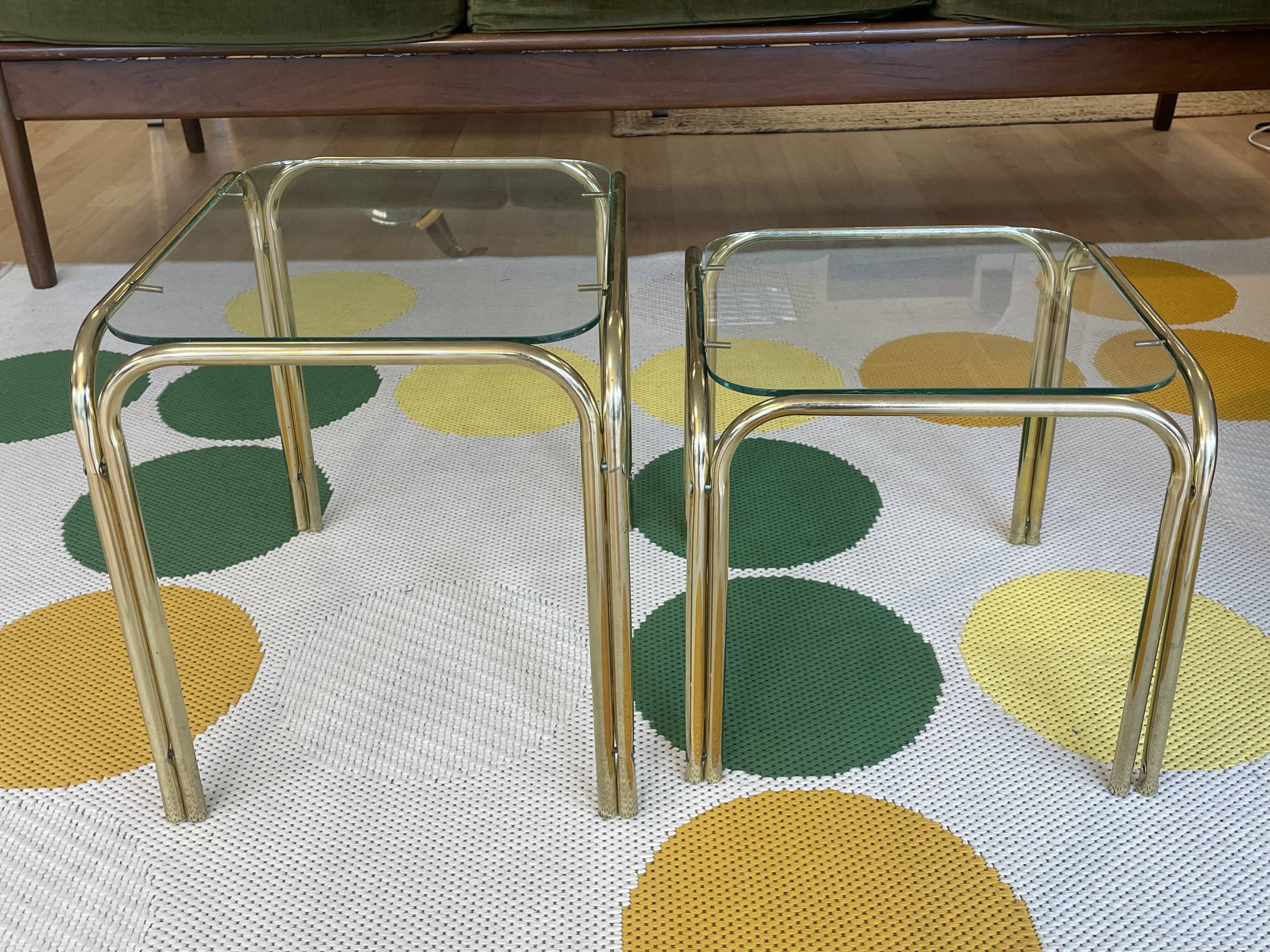 Pair of small nesting coffee tables in gold tubular metal & transparent glass tops