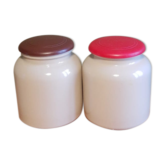 Duo of sandstone mustard pots with vintage red and brown lids